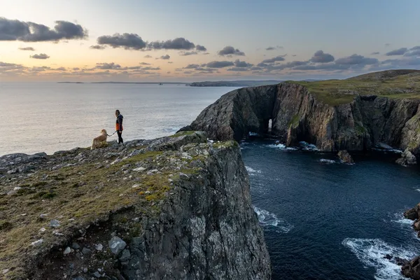 Person and a dog on a cliff